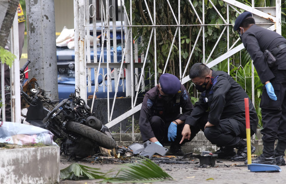 Members of a police bomb squad inspect the wreckage of a motorbike used to carry out Sunday's suicide bomb attack at the Sacred Heart of Jesus Cathedral in Makassar, South Sulawesi, Indonesia, Monday, March 29, 2021. Two attackers believed to be members of a militant network that pledged allegiance to the Islamic State group blew themselves up outside the packed Roman Catholic cathedral during a Palm Sunday Mass on Indonesia's Sulawesi island, wounding a number of people, police said. (AP Photo/Masyudi S. Firmansyah)