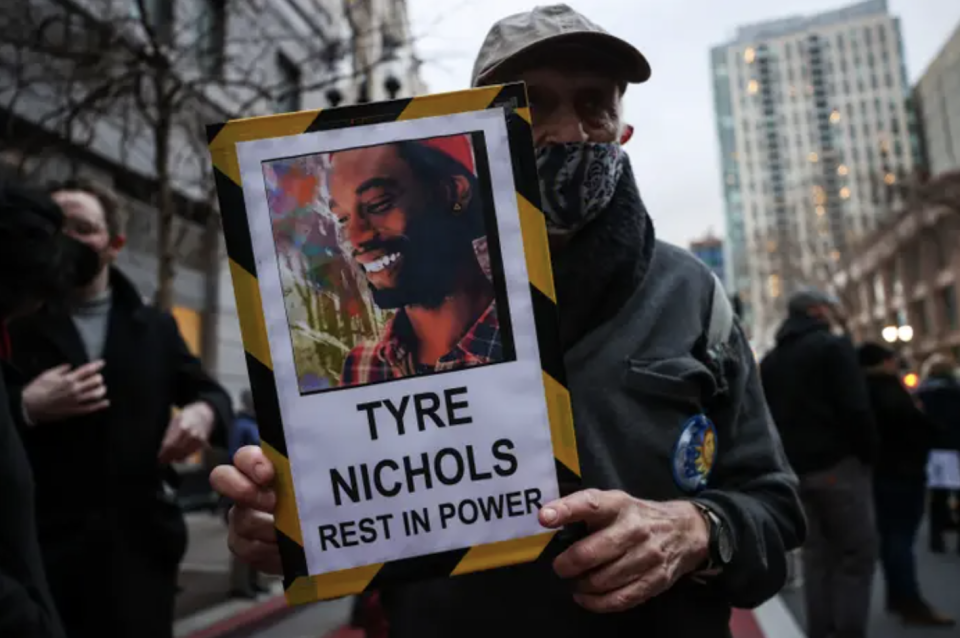 A man holds up a sign with a photo of Tyre Nichols that reads, "Tyre Nichols rest in power"