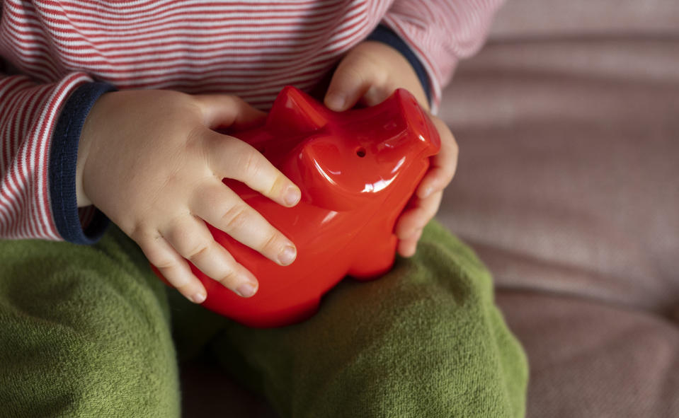 A child holds a piggy bank in his hands. (Source: Getty)