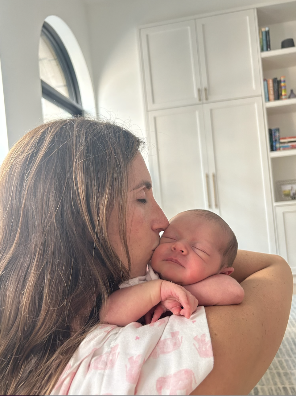 Hannah kissing her daughter on the cheek while holding her