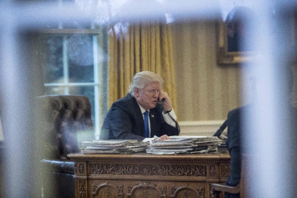 President Donald Trump speaks on the phone with German Chancellor Angela Merkel, Saturday, Jan. 28, 2017, in the Oval Office at the White House in Washington. (AP Photo/Andrew Harnik)