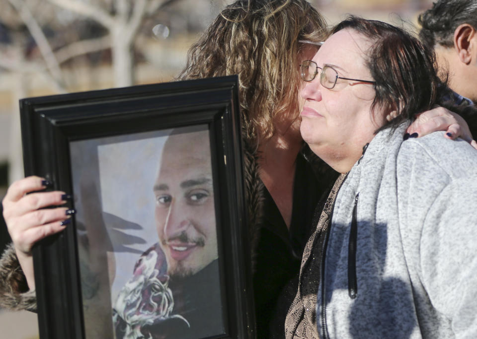 FILE - Lisa Finch, the mother of Andrew Finch, hugs Lorrie Hernandez, who is holding a portrait of Andrew Finch after the family held a press conference outside City Hall on Jan. 23, 2018, in Wichita, Kan. The city of Wichita on Tuesday, March 14, 2023, approved a $5 million settlement of a lawsuit filed by the family Andrew Finch, who was shot and killed by a police officer during a hoax call in 2017. (Travis Heying/The Wichita Eagle via AP, File)