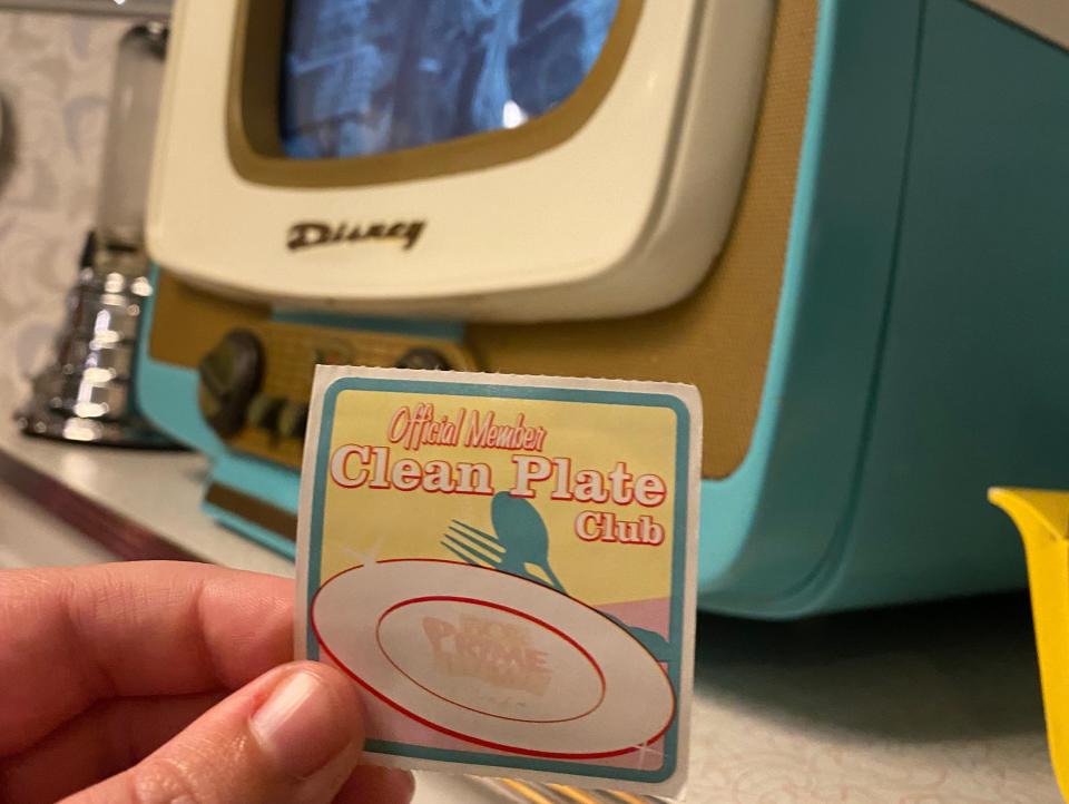 hand holding clean plate club sticker from 50s prime time cafe at hollywood studios