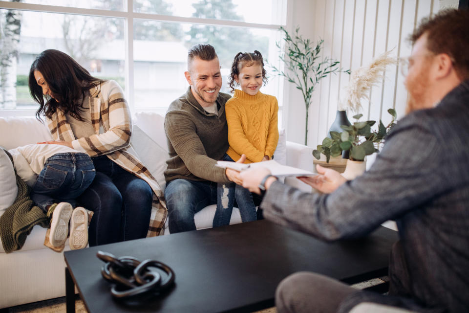 A Caucasian Real Estate Agent facilitates the signing of papers for the sale of a home to a multi-ethnic family to a viewing of a home they are interested in buying.  Shot in Washington state, USA.