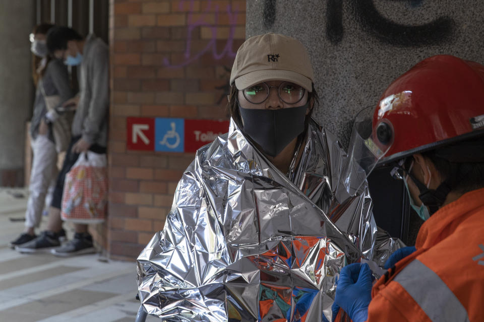 A woman is attended to by medics at the Hong Kong Polytechnic University in Hong Kong on Wednesday, Nov. 20, 2019. Hong Kong schools have reopened after a six-day shutdown but students were facing transit disruptions as the last protesters remained holed up on a university campus. (AP Photo/Ng Han Guan)