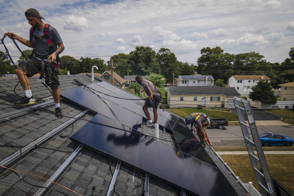 FILE - Employees of NY State Solar, a residential and commercial photovoltaic systems company, install an array of solar panels on a roof, Aug. 11, 2022, in the Long Island hamlet of Massapequa, N.Y. Electricity generated from renewables surpassed coal in the United States for the first time in 2022, the U.S. Energy Information Administration announced Monday, March 27, 2023. (AP Photo/John Minchillo, File)