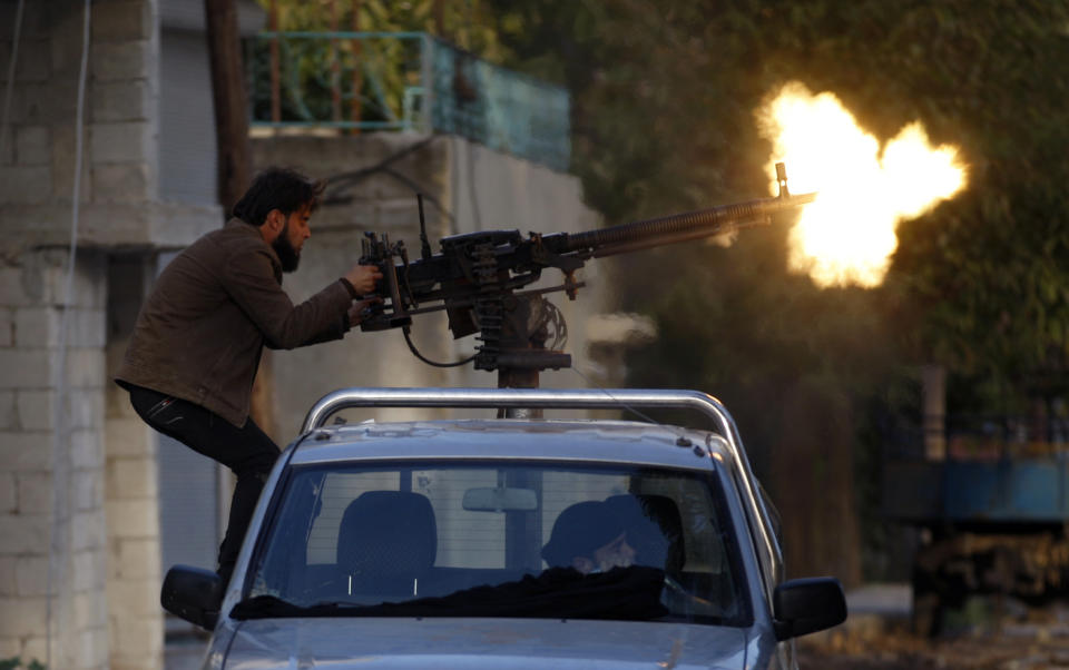 File - In this Saturday, Nov. 17, 2012 file photo, a Syrian fighter shoots during clashes with Syrian army forces in the town of Harem on the outskirts of Idlib, Syria. Syrians are marking 10 years since peaceful protests against President Bashar Assad's government erupted in March 2011, touching off a popular uprising that quickly turned into a full-blown civil war. (AP Photo/ Khalil Hamra, File)