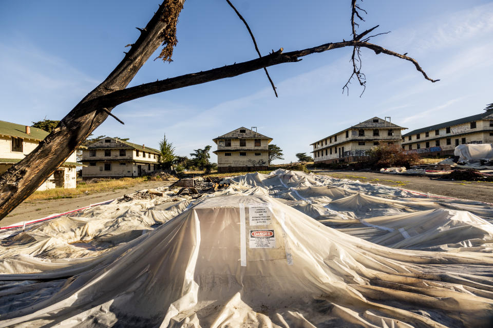 Labeled with asbestos and lead warnings, sheeting covers rubble from demolished barracks at Fort Ord on Thursday, April 29, 2021, in Fort Ord, Calif. In 1990, four years before it began the process of closing for active military training, Fort Ord was added to the Environmental Protection Agency’s list of the most polluted places in the nation. Included in that pollution were dozens of chemicals, some known to cause cancer, found in the base’s drinking water. (AP Photo/Noah Berger)