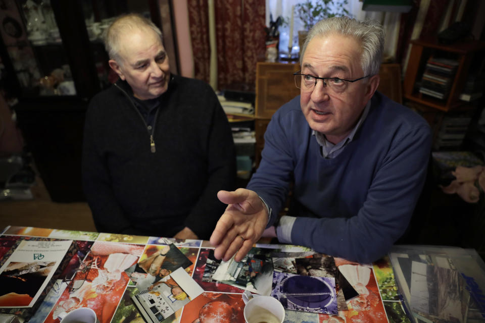 Former British Channel Tunnel worker Graham Fagg, left, and Former French Channel Tunnel worker Philippe Cozette sit with their photographs on the table in front of them, of their time working on the construction of the Channel Tunnel during an interview with The Associated Press at Graham's home in Dover, England, Thursday, Jan. 30, 2020. By digging their way to each other deep under the English Channel, tunnelers Graham Fagg and Philippe Cozette became symbols for British-French friendship when they made the first breakthrough in the Channel Tunnel nearly 30 years ago. (AP Photo/Matt Dunham)