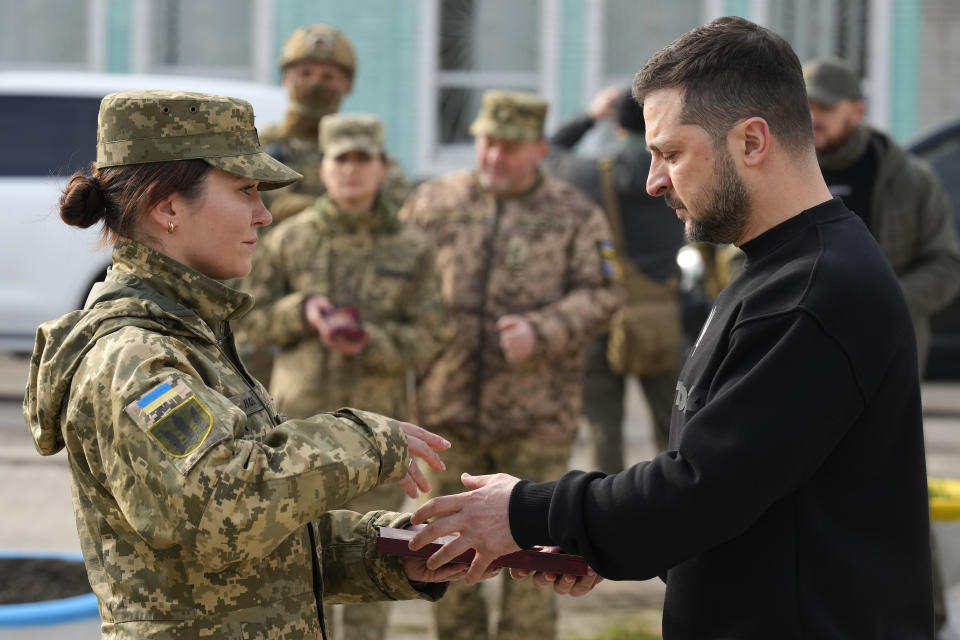 Ukrainian President Volodymyr Zelenskyy presents a medal to a servicewoman in Okhtyrka in the Sumy region of Ukraine, Tuesday March 28, 2023. (AP Photo/Efrem Lukatsky)