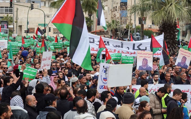 Demonstrators carry flags and banners during a protest in Amman