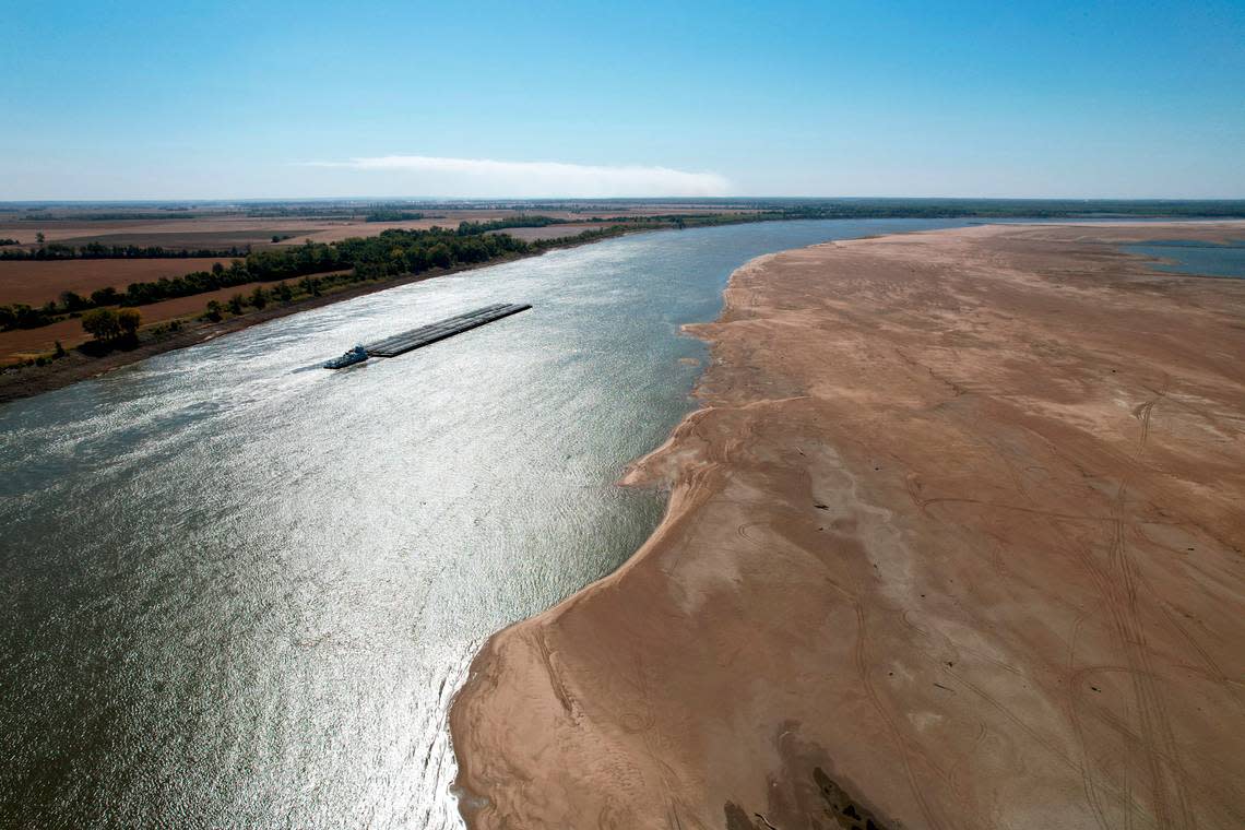 In this photo taken by a drone, a barge maneuvers its way down the normally wide Mississippi River where it has been reduced to a narrow trickle Thursday, Oct. 20, 2022, at Tiptonville, Tenn. The lack of rainfall in recent weeks has left the river approaching record low levels in areas from Missouri south through Louisiana, making barge and other navigation along the river more difficult.