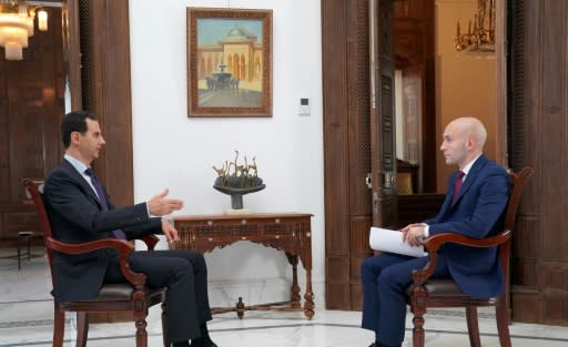 A handout picture released by the official Facebook page of the Syrian Presidency on May 31, 2018, shows Syrian President Bashar al-Assad (L) giving an interview to a journalist from Russia Today in the capital Damascus