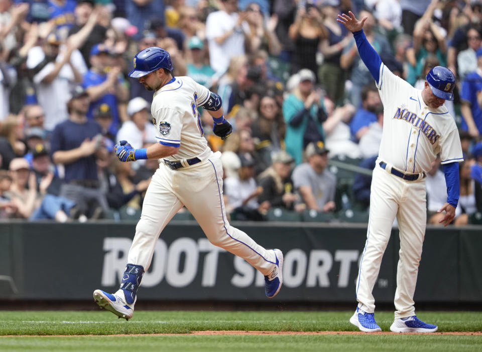 Seattle Mariners designated hitter Cal Raleigh, left, rounds third base after hitting a home run as third base coach Manny Acta, right, gestures during the fourth inning of a baseball game against the Pittsburgh Pirates, Sunday, May 28, 2023, in Seattle. (AP Photo/Lindsey Wasson)