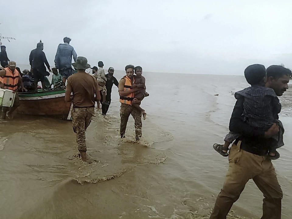 In this picture released by Pakistan's Sindh Rangers, paramilitary soldiers help to evacuate people from a village due to Cyclone Biparjoy approaching, at a costal area of Thatta district, in Pakistan's Sindh province, Tuesday, June 13, 2023. Pakistan's army and civil authorities are planning to evacuate 80,000 people to safety along the country's southern coast, and thousands in neighboring India sought shelter ahead of Cyclone Biparjoy, officials said. (Pakistan's Sindh Rangers via AP)