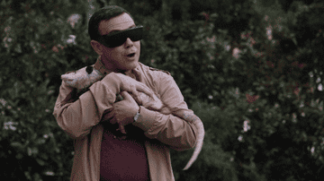 GIF of a man snuggling with an opposum