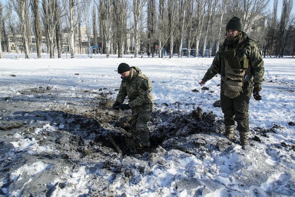 A Ukrainian soldier inspects a crater left by an explosion in Avdiivka, Ukraine, Tuesday, Jan. 31, 2017. Fighting between government troops and Russia-backed separatist rebels in eastern Ukraine escalated on Tuesday, killing at least eight people late Monday and early Tuesday, injuring dozens and briefly trapping more than 200 coal miners underground, the warring sides reported.(AP Photo/Inna Varenytsia)