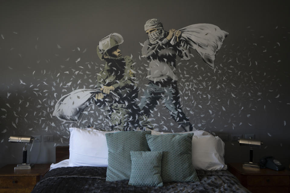 A Banksy wall painting showing Israeli border policeman and a Palestinian in a pillow fight is seen in one of the rooms of the The Walled Off Hotel in the West Bank city of Bethlehem, Sunday, June 19, 2022. Despite the roaring return of travelers, challenges and uncertainty cast shadows over the post-pandemic landscape. Full recoveries are generally not expected until at least 2024. (AP Photo/Maya Alleruzzo)