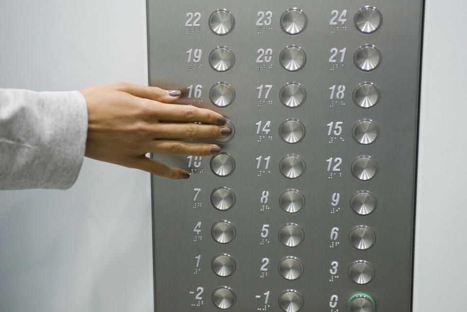 A hand pushing an elevator floor button