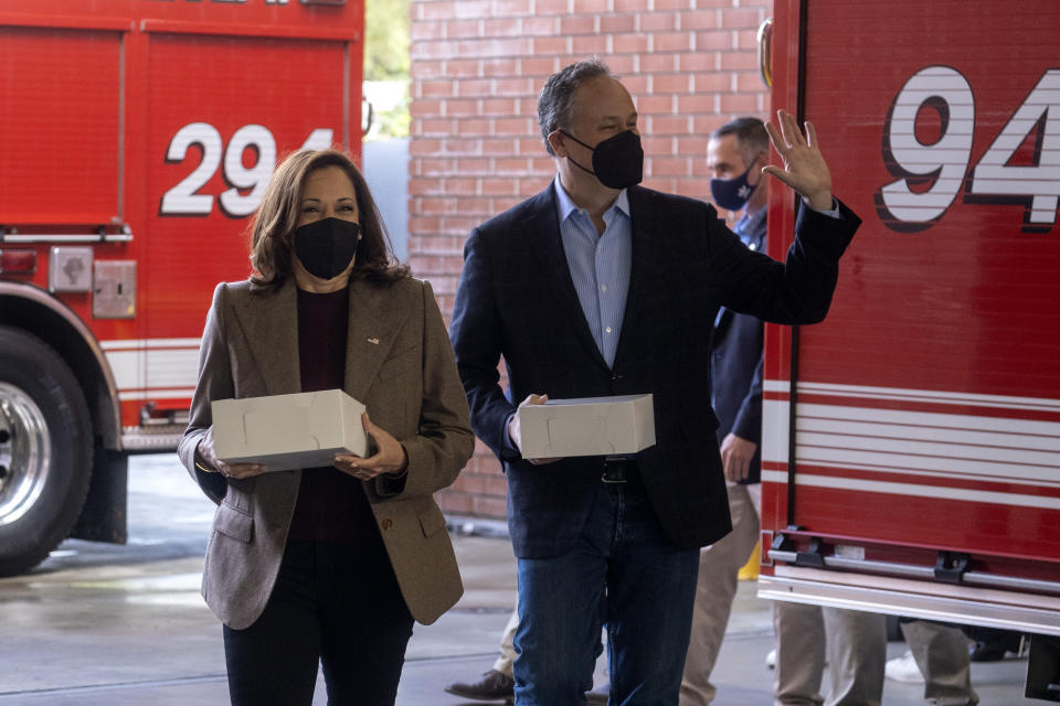 Vice President Kamala Harris, left, wearing a face mask, accompanied by her husband, Douglas Emhoff, arrives at the Los Angeles Fire Department Station 94, in Los Angeles, Friday, Dec. 24, 2021. (AP Photo/Ringo H.W. Chiu)