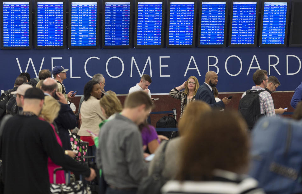 Passengers wait in line to check luggage as flight schedules are projected on screens in Atlanta, Ga, Wednesday, April 5, 2017. Flights have resumed at Atlanta's airport, but stormy weather continues to cause delays for both departing and arriving flights. (David Barnes/Atlanta Journal-Constitution via AP)