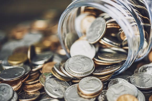 Coins spilling out of a jar onto a flat surface.