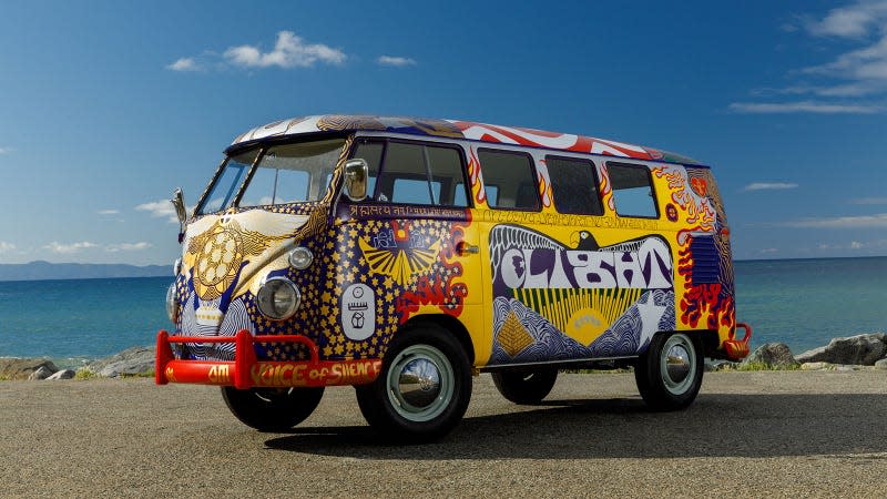 A photo of an elaborately painted VW bus next to the ocean. 