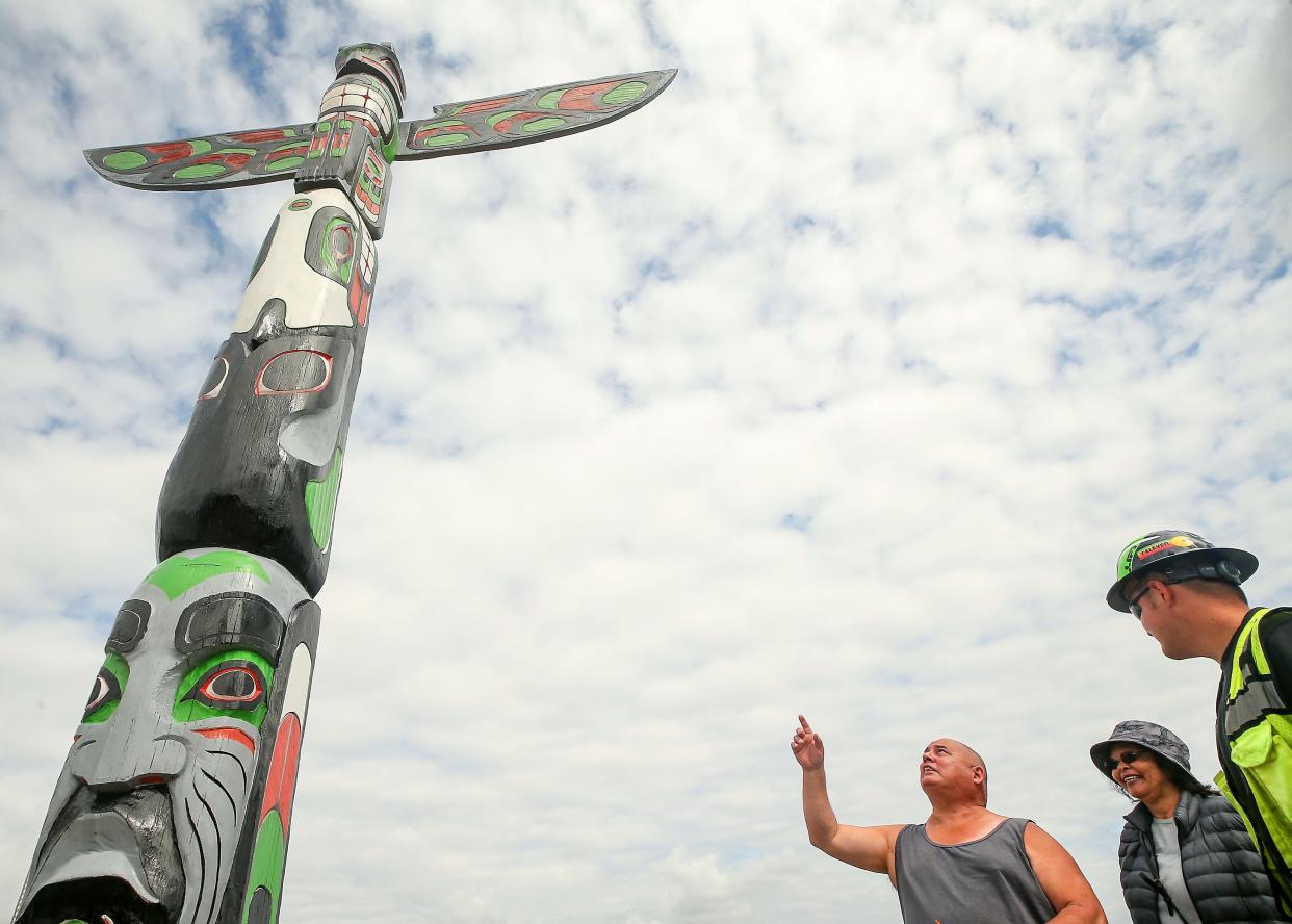 With his wife Lurita smiling beside him Bill Martin Jr., left, points to an area of the totem pole as he talks about the restoration work with Port Orchard Public Works’s Jonathan Hubbard, right, after Hubbard and fellow crew members put the restored totem pole back into place at the end of Sidney Ave. on the waterfront in Port Orchard on Wednesday, Aug. 30, 2023. Martin, a member of the Makah Tribe in Neah Bay, is the grandson of the original carver of the totem pole Frank Smith.