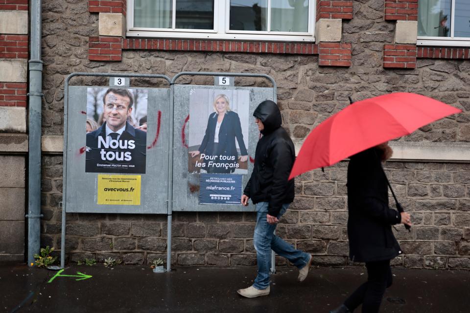 People walk past election posters in Nantes, western France, on Sunday (AP)