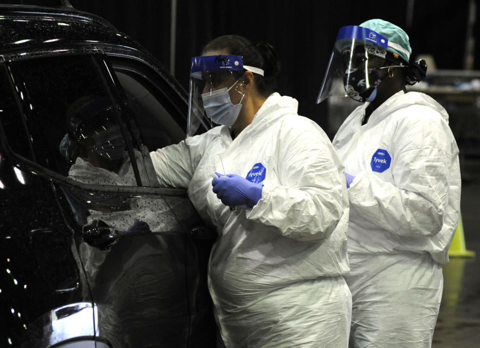 FILE - In this Aug. 12, 2021 file photo, workers from USA Health test a person for COVID-19 during a drive-up clinic in Mobile, Ala. Health officials say they are seeing a spike in cases among young adults and children as the highly contagious delta variant sweeps through unvaccinated populations. (AP Photo/Jay Reeves, File)