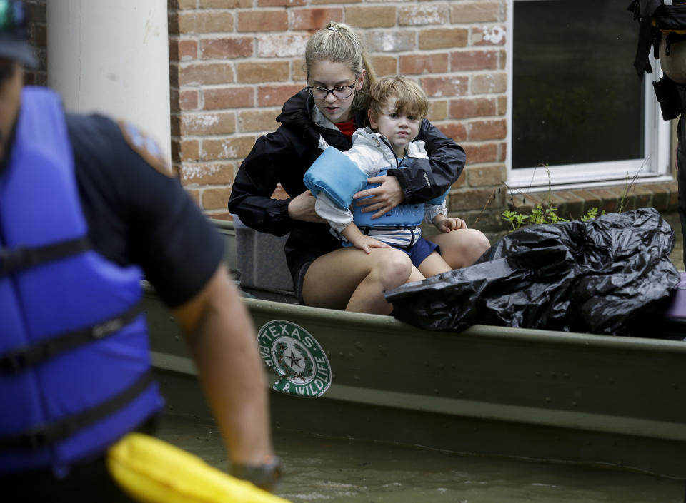 A woman and small child sit in a Texas Game Warden boat after evacuating a flooded home in the Lochshire neighborhood Friday, Sept. 20, 2019, in Huffman, Texas. Emergency workers used boats Friday to rescue about 60 residents of a Houston-area community still trapped in their homes by floodwaters following one of the wettest tropical cyclones in U.S. history. (Godofredo A. Vásquez/Houston Chronicle via AP)