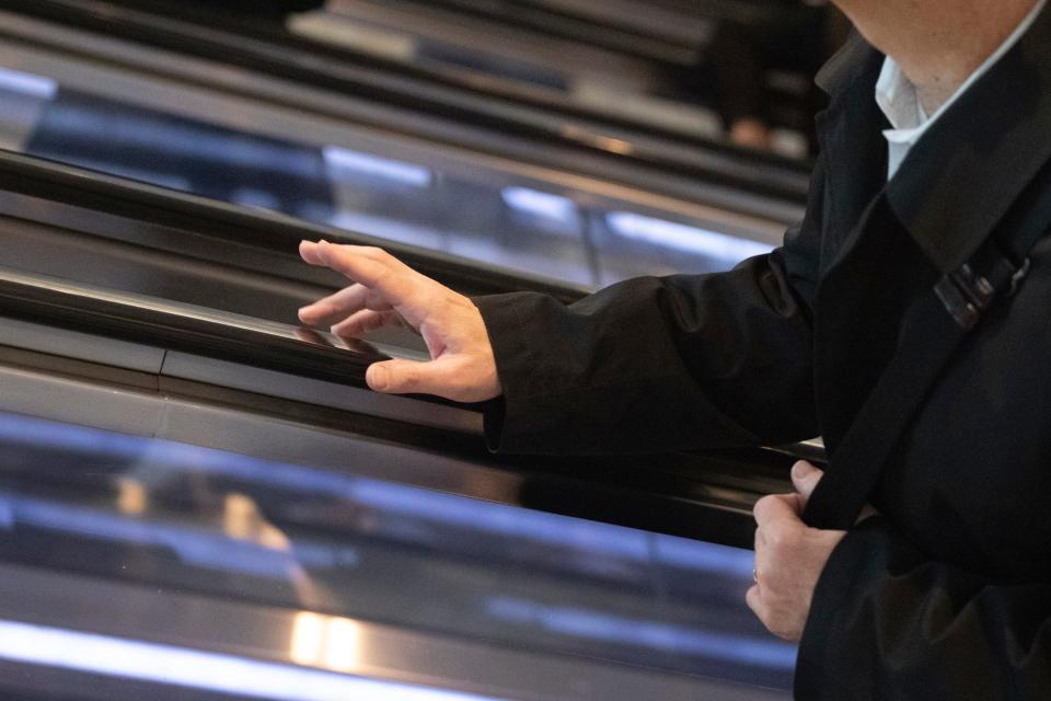 A commuter holds on to an escalator handrail as he exits the World Trade Center transportation hub, Wednesday, March 4, 2020, in New York.