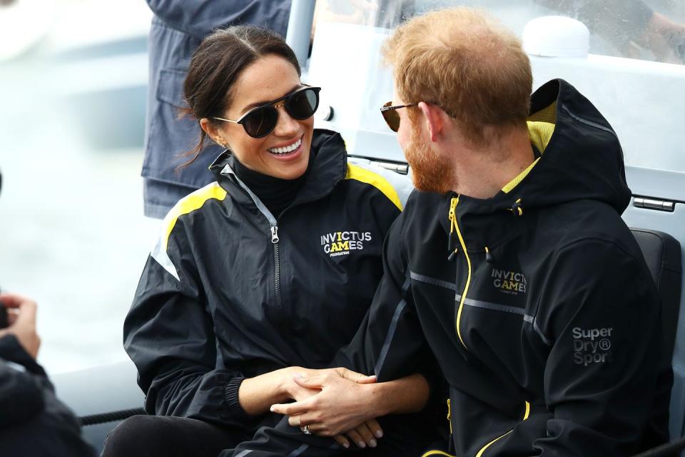 Prince Harry and Meghan Markle link arms while watching a sailing race in Sydney.