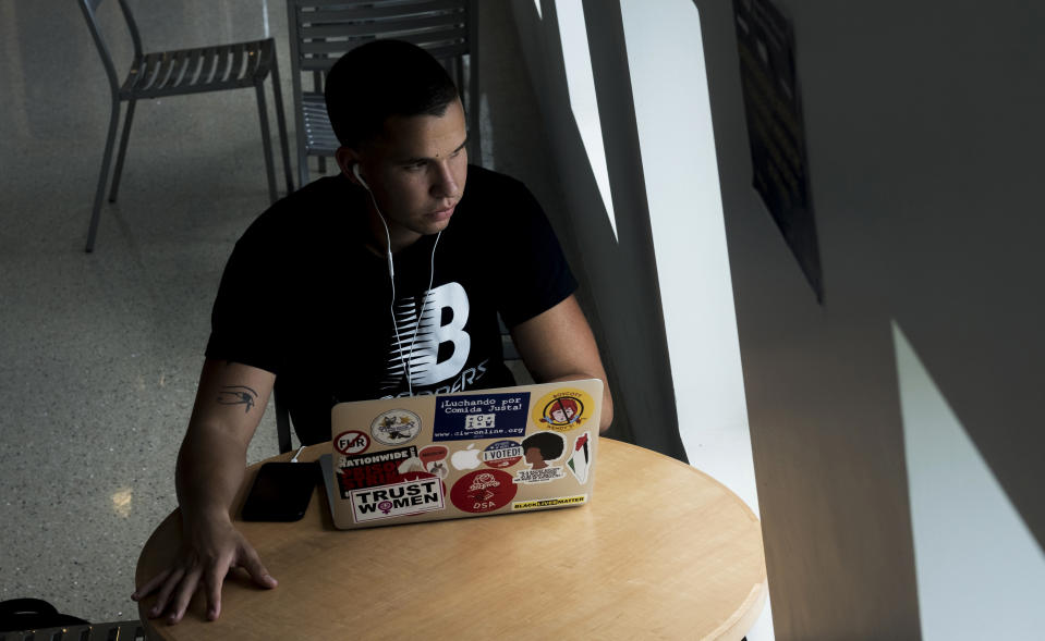 In this June 26, 2019, photo, Andy Vila, 21, speaks to callers who have phoned in to an anonymous know-your-rights hotline for immigrants who are in Miami illegally. He says his generation is more concerned with solving current problems than fighting past ideological wars. (AP Photo/Ellis Rua)