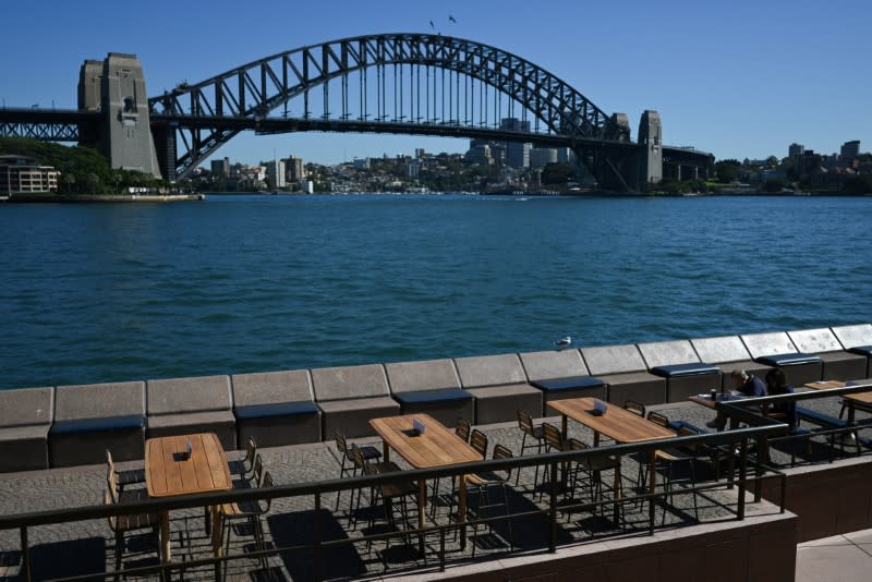 Tables at an open restaurant are seen mostly deserted on a quiet morning at the waterfront of the Sydney Opera House in Sydney