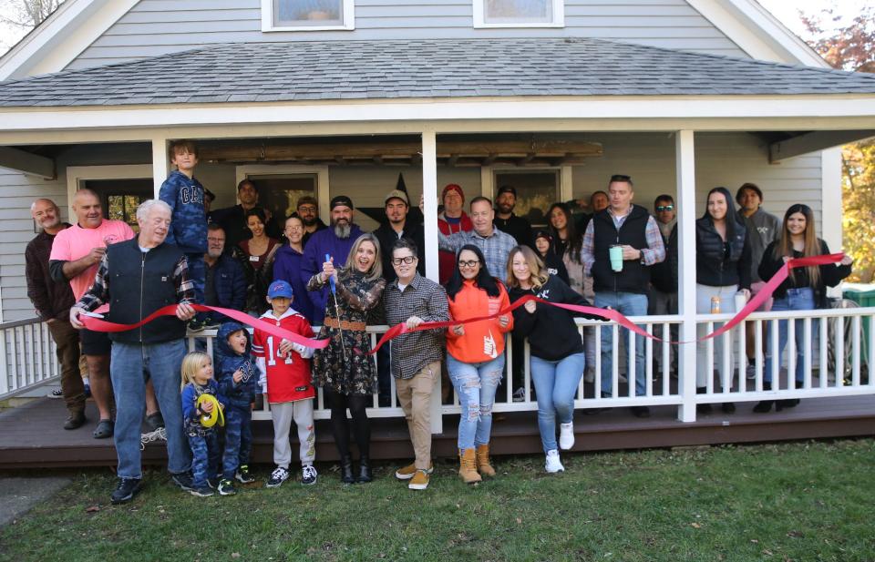 Rusty Bridle of the Hampton Chamber of Commerce, left, holds the ribbon as Sandi Coyle cuts it for the grand reopening of Magnolia House in Hampton Sunday, Nov. 12, 2023. Founder/CEO Jules Johnson is next to Coyle.