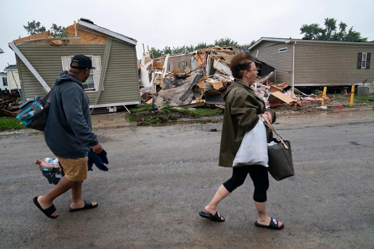 Sean Johnson walks with his girlfriend Angela Taylor to check out thier Frenchtown Villas Monroe home in Newport, Mich., on Friday, Aug. 25, 2023, after a heavy band of storms hit the region on Thursday. The couple looks as they pass a home at the corner of Chalet and Killy that was destroyed by the storms. (Mandi Wright/Detroit Free Press via AP)