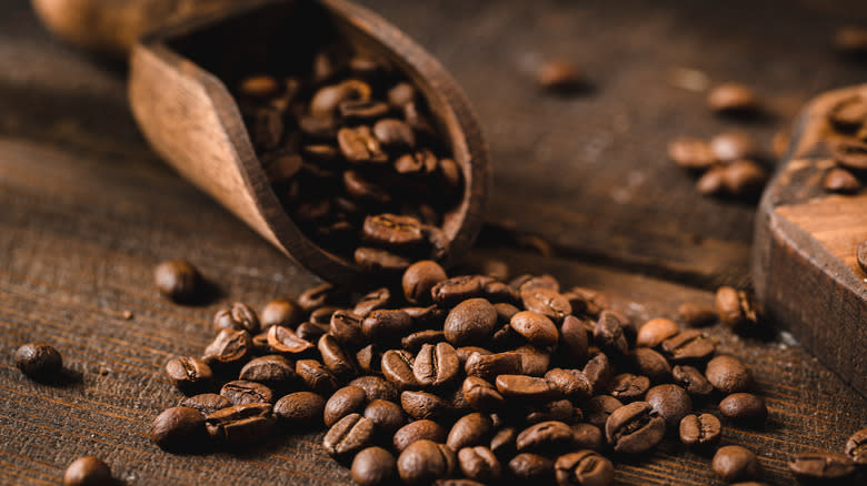 Coffee beans spilling out of serving scoop on table