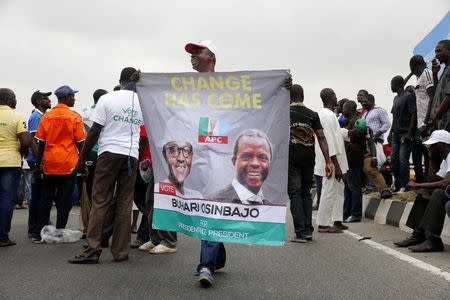 A man holds a banner campaigning for All Progressives Congress (APC) Presidential and vice Presidential candidates Muhammadu Buhari and Yemi Osinbajo during a street procession tagged 'March for Change' in Lagos March 7, 2015. REUTERS/Akintunde Akinleye