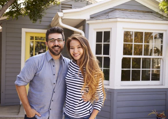 young man and woman standing in front of house with arms around each other and smiling