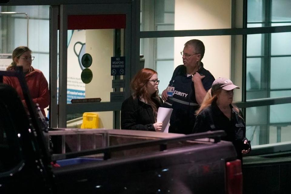 People depart an emergency department entrance at Central Maine Medical Center, past a member of security, behind right, during an active shooter situation, in Lewiston, Maine, Wednesday, Oct. 25, 2023. (AP Photo/Steven Senne)