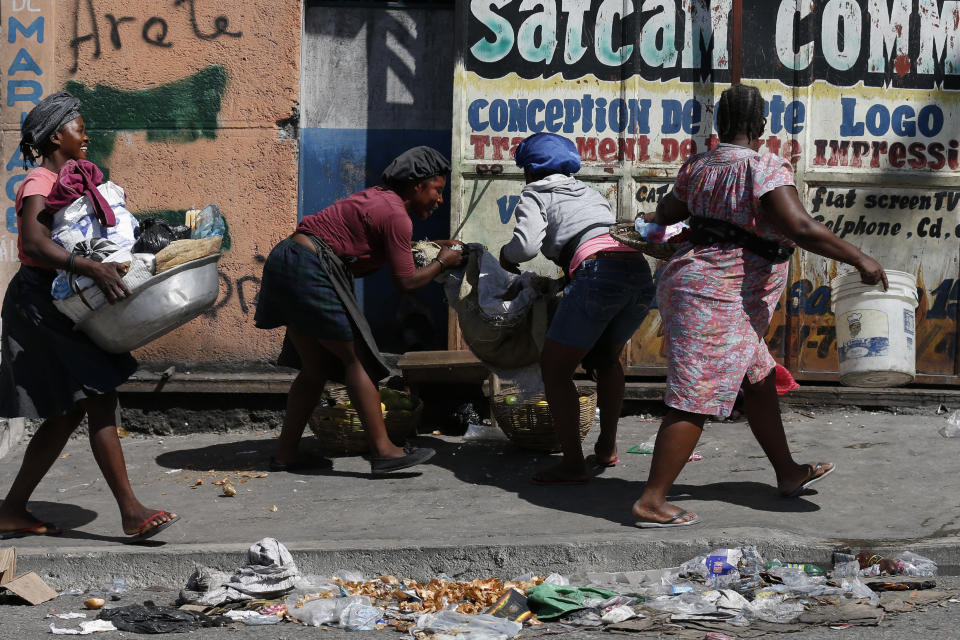 Vendors scramble to pack up their goods and get inside, as protesters calling for President Jovenel Moïse march up a road in downtown Port-au-Prince, Haiti, Monday, Oct. 21, 2019. Anger over corruption, inflation and scarcity of basic goods including fuel has led to large demonstrations that began more than a month ago and have shuttered many businesses and schools.(AP Photo/Rebecca Blackwell)