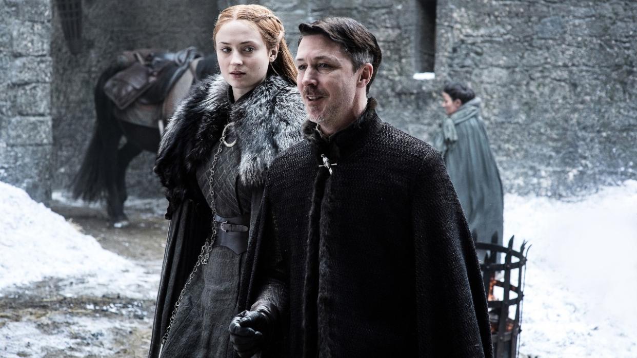 Aidan Gillen standing in front of Sophie Turner on Game of Thrones. 