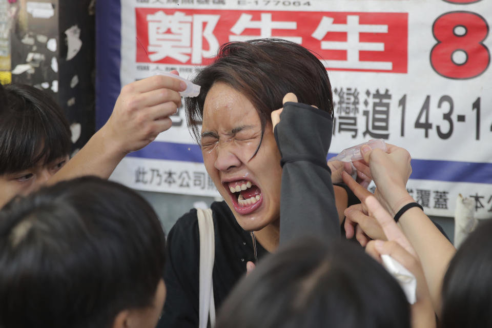 A woman reacts after being pepper sprayed by police in Hong Kong Monday, Nov. 11, 2019. Police in Hong Kong were filmed shooting at least one protester and possibly a second on Monday as demonstrators blocked subway lines and roads during the morning commute. (AP Photo/Kin Cheung)