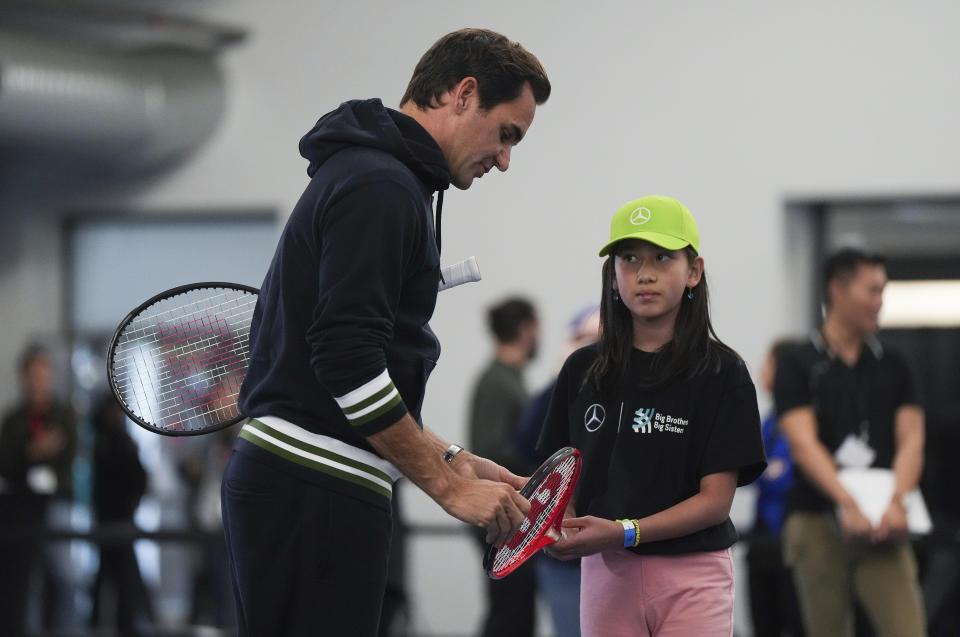 Retired tennis player Roger Federer gives instructions to Kiana De Laurentiis, 10, during a tennis clinic for kids from the Vancouver chapters of Big Brothers and Big Sisters, as part of a partnership with Mercedes-Benz Canada, in Vancouver, British Columbia, Tuesday, Sept. 19, 2023. Federer is in the city for the Laver Cup tennis tournament that he co-founded. (Darryl Dyck/The Canadian Press via AP)