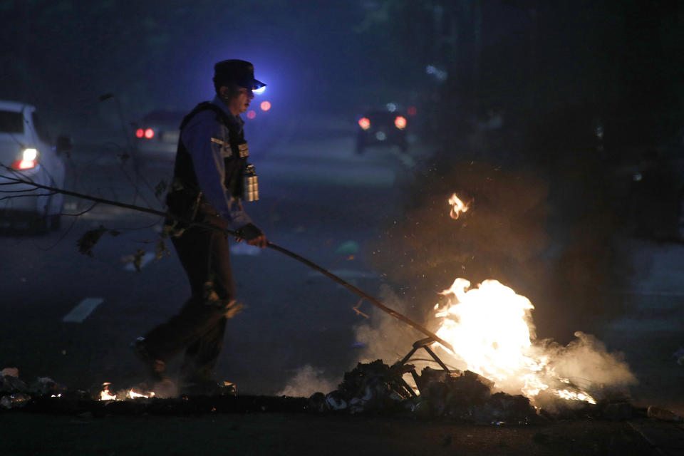 A police officer dismantles a burning barricade, during a night of rioting in Tegucigalpa, Honduras, late Thursday, June 20, 2019. Protesters blockaded highways, clashed with police as part of demonstrations against President Juan Orlando Hernández. (AP Photo/Elmer Martinez)