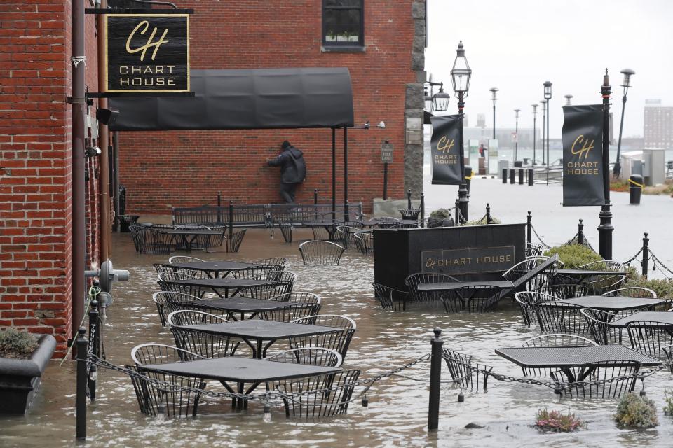 Water floods a restaurant terrace during high tide on Long Wharf, Friday, Dec. 23, 2022, in Boston. Winter weather is blanketing the U.S. More than 200 million people — about 60% of the U.S. population — were under some form of winter weather advisory or warning on Friday. (AP Photo/Michael Dwyer)