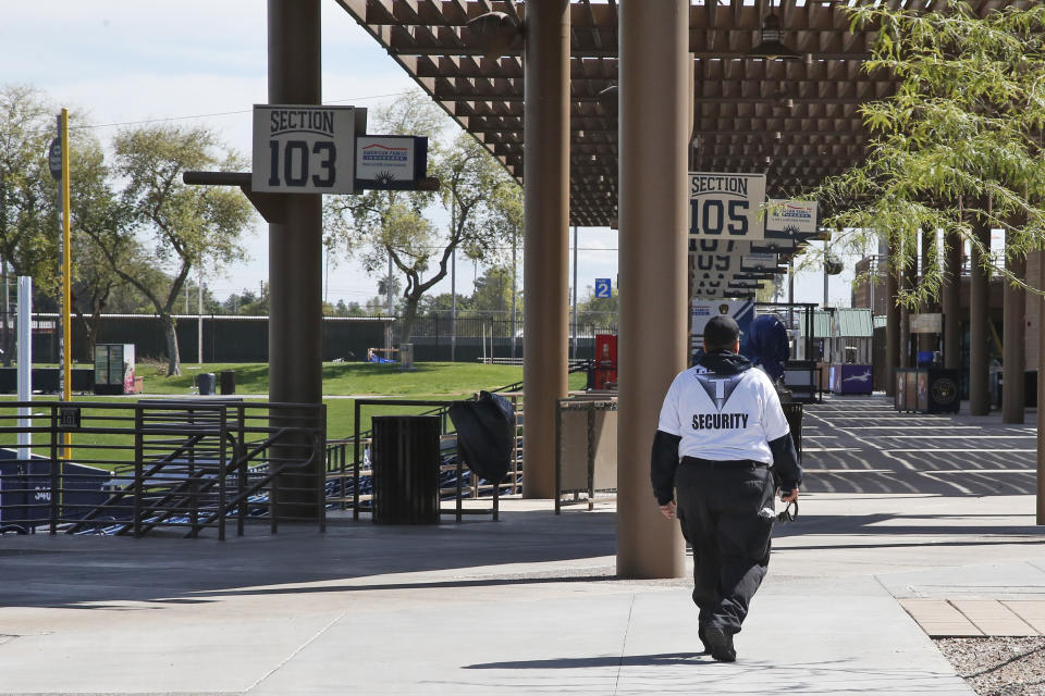 A security guard, walks through an empty American Family Fields, the spring training home of the Milwaukee Brewers, in Phoenix, Sunday, March 15, 2020. The remainder of spring training baseball games have been canceled due to the coronavirus. (AP Photo/Sue Ogrocki)