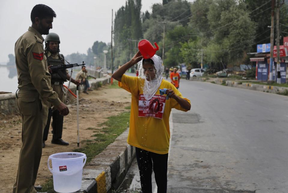 <p>Ein indischer Polizist reicht einer Teilnehmerin des „Run for Peace“-Marathons eine Erfrischung. (Bild: Mukhtar Khan/AP/dpa) </p>