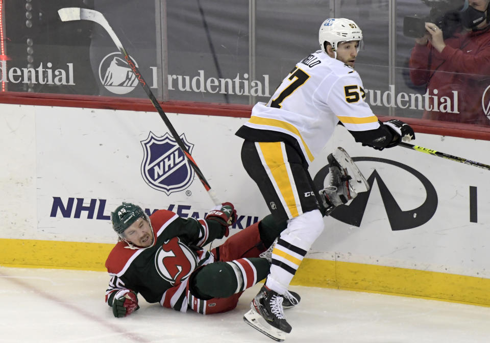 Pittsburgh Penguins center Anthony Angello (57) checks New Jersey Devils defenseman Sami Vatanen (45) to the ice during the first period of an NHL hockey game Saturday, March 20, 2021, in Newark, N.J. (AP Photo/Bill Kostroun)